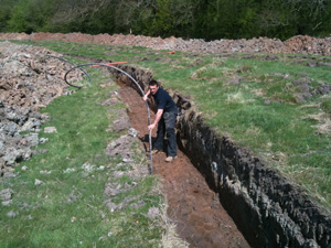 Ashley in a trench laying a ground loop collector pipe in Whitchurch, Shropshire